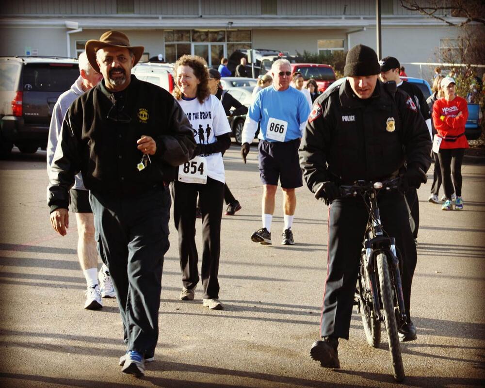 An officer riding a bike next to individuals in a marathon.