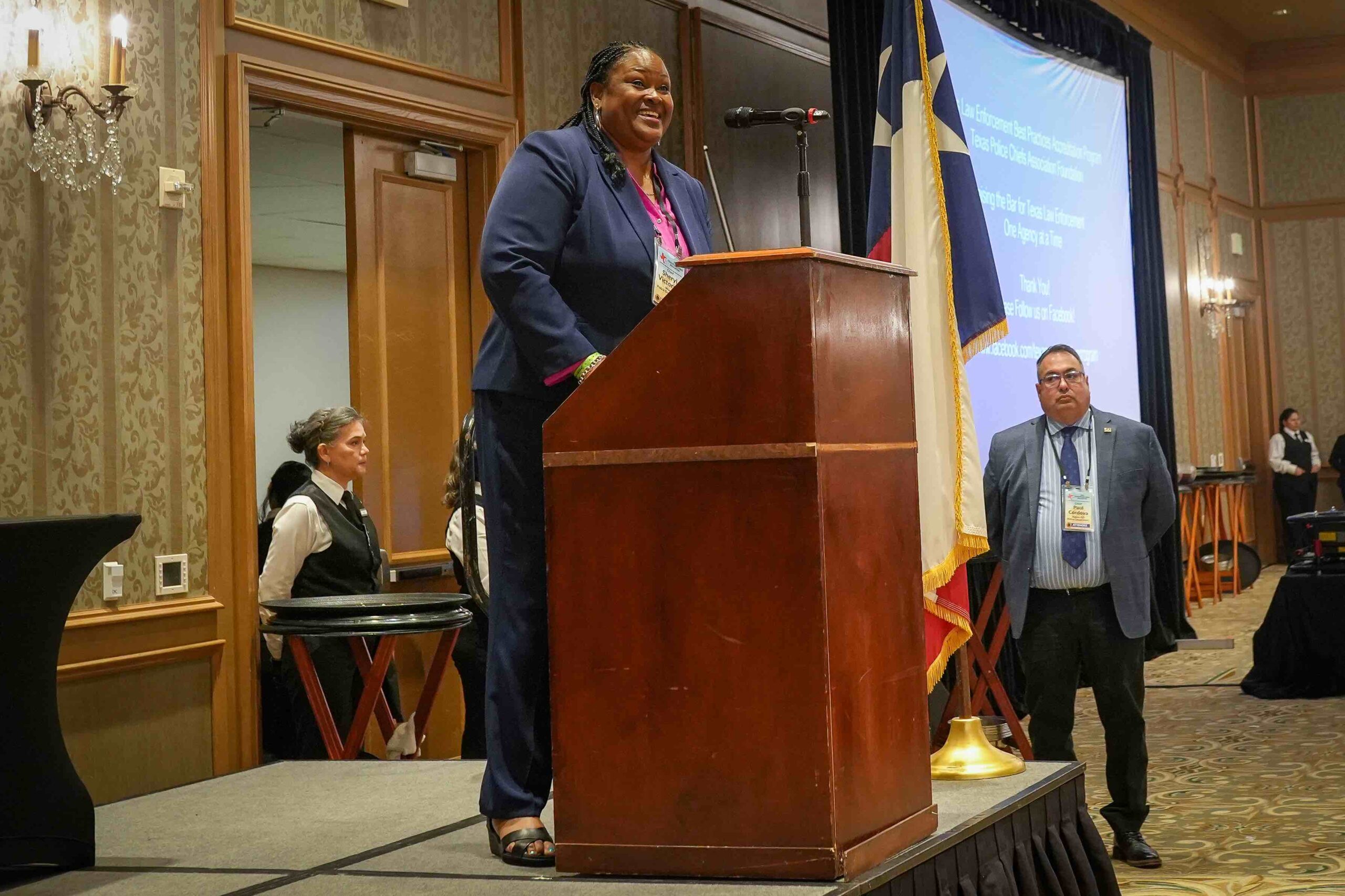A black female police officer makes a speech at a podium.